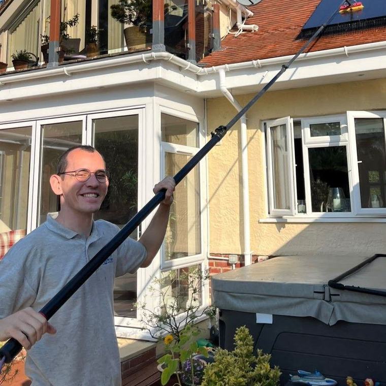 Christopher using a water-fed pole to clean the outside of a house
