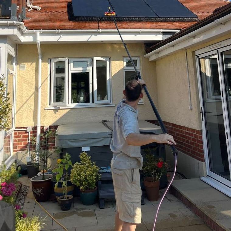 Christopher cleaning solar panels with a water-fed pole